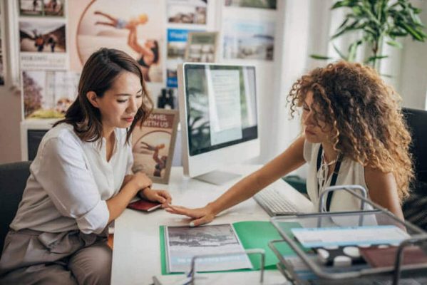 Two people, woman in modern travel agency talking with a female travel agent, she is planning a vacation..
